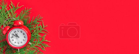 Foto de Reloj despertador con ramas de árbol sobre fondo de papel rojo. 5 minutos antes del Año Nuevo. Tarjeta de felicitación creativa - Imagen libre de derechos