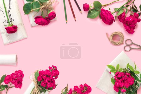 Foto de Set de papel de regalo y flores para hacer a mano sobre fondo rosa. Regalos hechos en casa caja de artesanía con ramo de rosas rojas - Imagen libre de derechos
