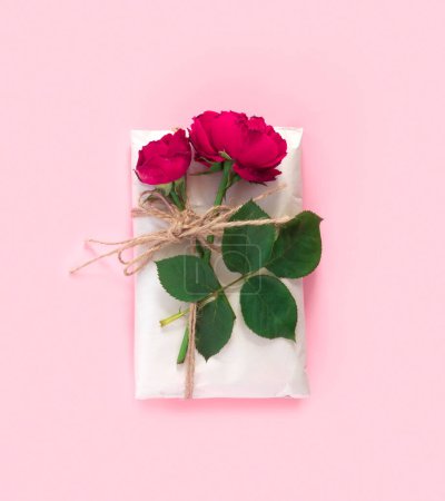 Foto de Set de papel de regalo y flores para hacer a mano sobre fondo rosa. Regalos hechos en casa caja de artesanía con ramo de rosas rojas - Imagen libre de derechos