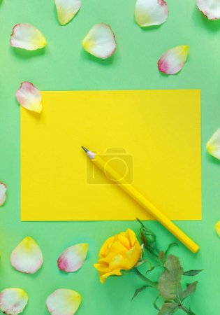 Téléchargez les photos : Bouquet de belles roses jaunes et pétales de fleurs sur fond de papier vert. Félicitations ou invitation à la fête - en image libre de droit