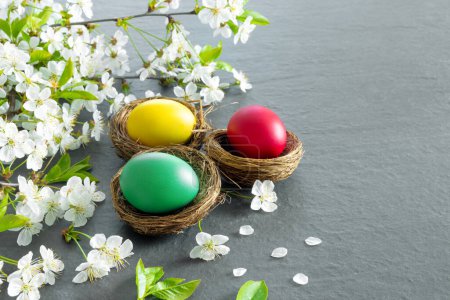 Foto de Nidos de pollo con huevos de Pascua pintados sobre una mesa oscura. Tarjeta de felicitación de vacaciones. Concepto de bandera creativa - Imagen libre de derechos