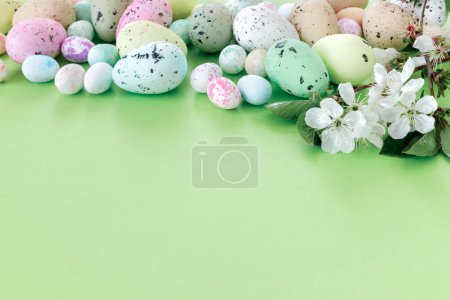 Foto de Hermosa tarjeta de Pascua con huevos coloridos y ramas de cereza sobre fondo verde papel. Tarjeta de felicitación floral con copyspace para su texto. - Imagen libre de derechos