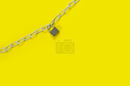 Foto de The padlock and chains on yellow background. Flat lay, top view with copy space for text. Banner. - Imagen libre de derechos