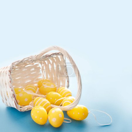 Foto de Concepto dulce Símbolos de Pascua de color amarillo y verde huevos en cesta sobre fondo de papel azul. - Imagen libre de derechos