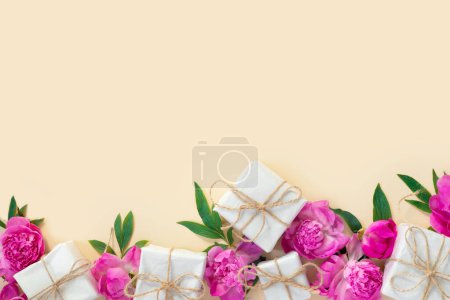 Téléchargez les photos : Bouquet de belles pivoines roses avec des boîtes-cadeaux en papier d'emballage sur fond jaune. Carte de vœux festive. Arrière-plan créatif avec espace de copie pour texte. - en image libre de droit