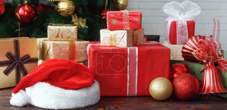 Photo for Gift boxes with beads, toys and Santa Claus hat on vintage wooden table  in Christmas - Royalty Free Image