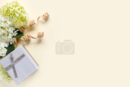 Foto de Hermoso ramo de hortensias con caja de regalo sobre fondo beige. Tarjeta de felicitación con corazones. Fondo creativo con espacio de copia para texto. - Imagen libre de derechos
