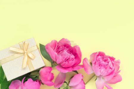 Téléchargez les photos : Bouquet de belles pivoines roses avec des boîtes-cadeaux en papier d'emballage sur fond jaune. Carte de vœux festive. Arrière-plan créatif avec espace de copie pour texte. - en image libre de droit