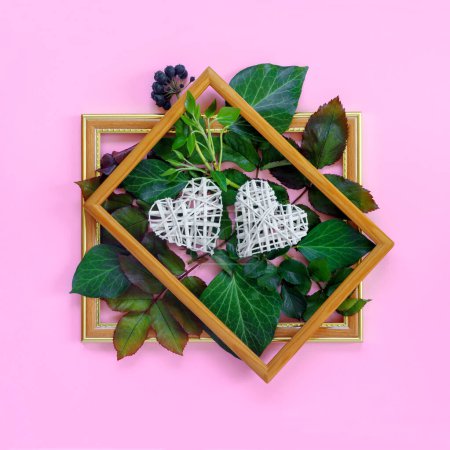 Téléchargez les photos : Belles roses blanches avec feuillage vert et coeurs dans un cadre en bois vintage sur un mur rose vif pour la Saint-Valentin. Carte de vœux créative - en image libre de droit