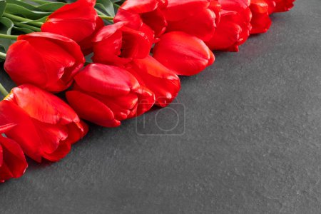 Foto de Ramo de hermosos tulipanes rojos en monumento de granito negro con espacio vacío para el texto - Imagen libre de derechos