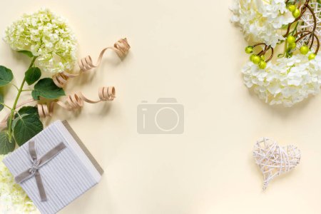 Téléchargez les photos : Beau bouquet d'hortensias avec coffret cadeau sur fond beige. Carte de voeux avec des cœurs. Arrière-plan créatif avec espace de copie pour texte. - en image libre de droit