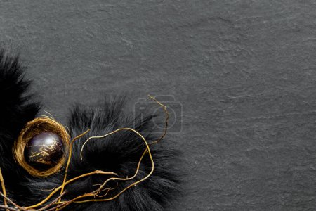 Téléchargez les photos : Nid en fourrure noire avec des œufs peints sur une table en pierre sombre. Bannière festive de Pâques avec des branches. Conception conceptuelle - en image libre de droit