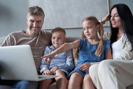 padres y sus hijos pequeños usando el ordenador portátil en casa juntos