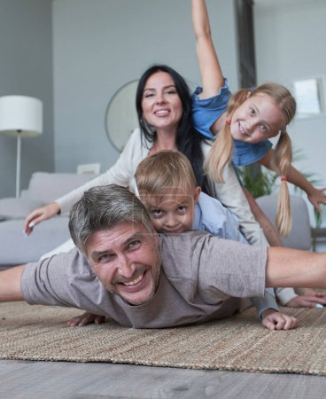 Téléchargez les photos : Jeune famille de quatre personnes qui s'amuse à la maison souriant - en image libre de droit