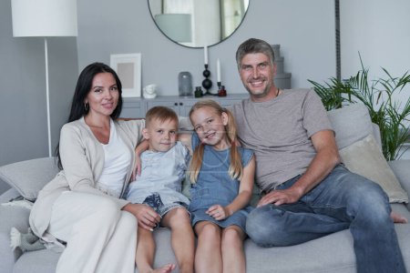 Photo for Family sitting in living room smiling at home - Royalty Free Image
