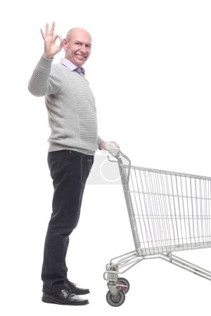 Foto de En pleno crecimiento. un hombre feliz con un carrito de compras. aislado sobre un fondo blanco. - Imagen libre de derechos