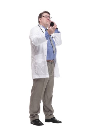Photo for In full growth. qualified doctor with a smartphone.isolated on a white background. - Royalty Free Image