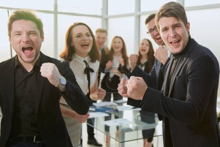 Téléchargez les photos : Heureuse équipe d'affaires est debout dans le bureau applaudissant. le concept de succès. - en image libre de droit