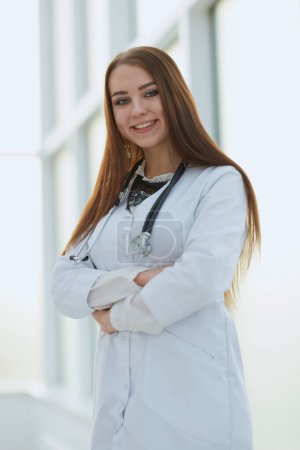 Foto de Joven doctora con portapapeles de pie en el vestíbulo del hospital. - Imagen libre de derechos