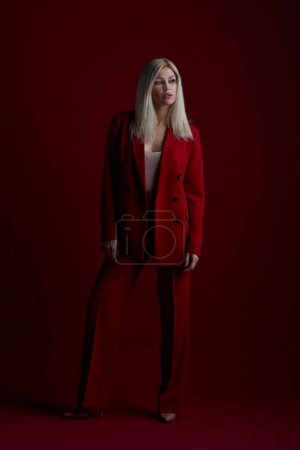 Téléchargez les photos : Portrait d'une femme blonde en robe rouge sur fond rouge - en image libre de droit