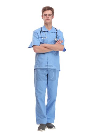 Téléchargez les photos : Chirurgien portant un uniforme bleu avec stéthoscope debout avec les bras repliés isolés sur blanc - en image libre de droit