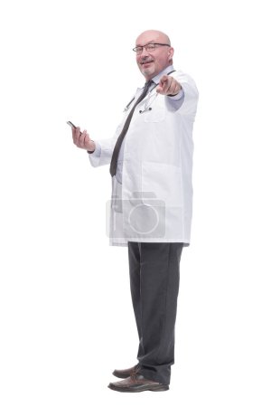 Téléchargez les photos : Full-length. mature doctor with smartphone. isolated on a white background. - en image libre de droit