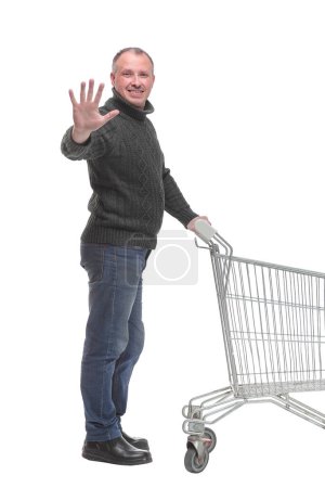 Photo for Full length portrait of a man returning an empty shopping cart isolated on white background - Royalty Free Image