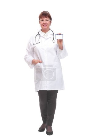 Téléchargez les photos : Femme médecin senior montrant la carte de visite sur un fond blanc et regardant la caméra - en image libre de droit
