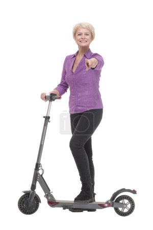 Téléchargez les photos : En pleine croissance. femme mûre souriante avec un scooter électrique. isolé sur un fond blanc. - en image libre de droit