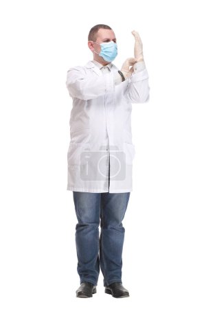Téléchargez les photos : Le jeune médecin met des gants et porte un masque médical. Concept médical corona virus - en image libre de droit