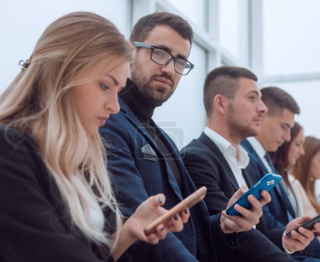 Photo for Close up. group of young business people looking at their smartphone screens. - Royalty Free Image