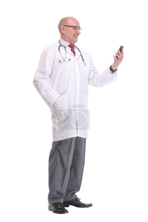 Photo for Portrait of happy senior smiling doctor holding smartphone. White isolated background. - Royalty Free Image