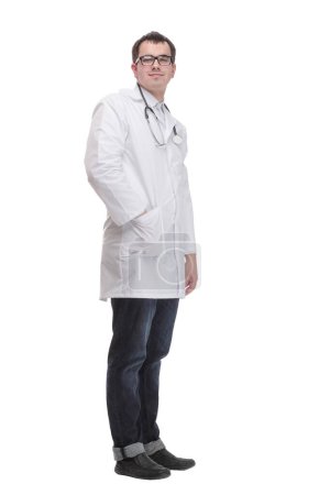 Téléchargez les photos : Jeune homme médecin vêtu d'un manteau blanc et stéthoscope avec sourire sur le visage, pointant la main et le doigt vers le côté - en image libre de droit