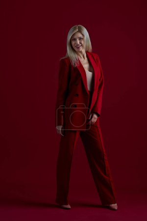 Photo for Portrait of a blonde woman in red dress on a red background - Royalty Free Image