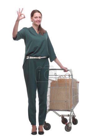 Photo for Full length portrait of a woman pushing a shopping trolley isolated on white background - Royalty Free Image