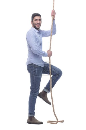 in full growth. ambitious young man climbing a rope. isolated on a white background.