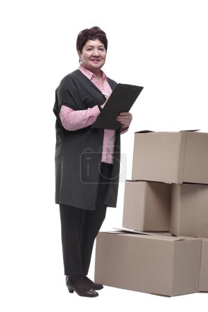Téléchargez les photos : En pleine croissance. une femme avec un presse-papiers debout près des boîtes en carton. isolé sur un blanc - en image libre de droit