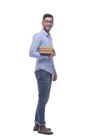 Téléchargez les photos : Vue latérale. jeune homme décontracté avec une pile de livres. isolé sur un fond blanc. - en image libre de droit