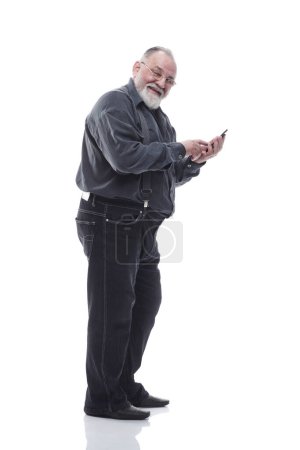 Foto de Vista lateral. sonriente anciano escribiendo en su smartphone aislado sobre un fondo blanco. - Imagen libre de derechos