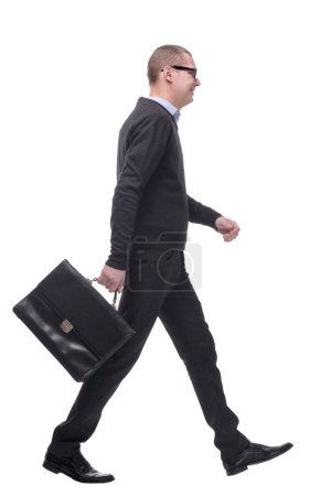 Photo for Full length side view picture of a young business man walking with a suitcase in his hand and a smile on his face. on white background - Royalty Free Image