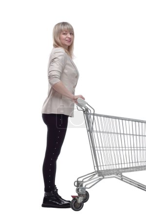 Foto de Vista lateral. mujer rubia con un carrito de compras mirando hacia el futuro. aislado sobre un fondo blanco. - Imagen libre de derechos