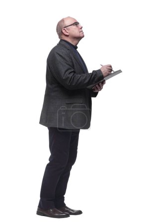 Téléchargez les photos : Vue latérale. homme d'affaires concentré prenant des notes dans le presse-papiers. isolé sur un fond blanc - en image libre de droit