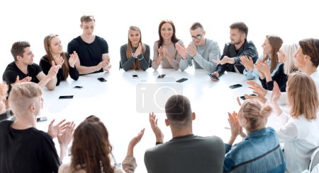 group of young people applauding, sitting at a round table . photo with copy space