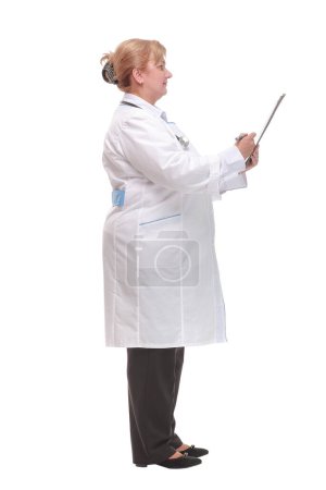 Foto de Retrato de vista lateral de una doctora experimentada escribiendo informes de pacientes y mirando hacia otro lado - Imagen libre de derechos