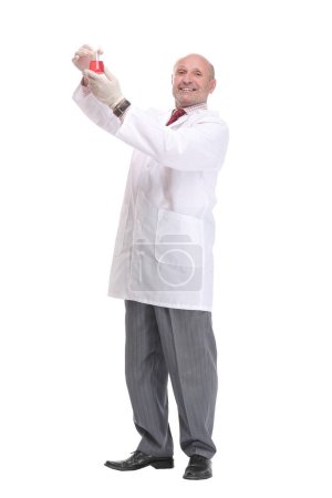Foto de Científico maduro con pelo gris y barba en bata blanca de pie con vaso de precipitados en la mano y con examen médico aislado sobre fondo blanco - Imagen libre de derechos
