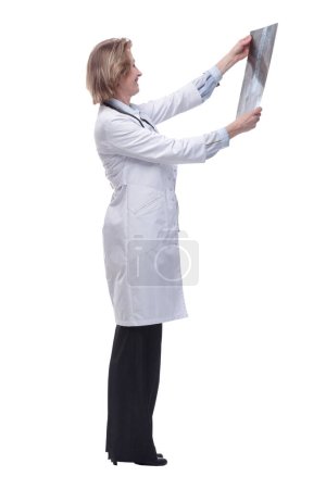 Téléchargez les photos : Vue latérale du médecin femme mature tenant une radiographie et l'examinant - en image libre de droit