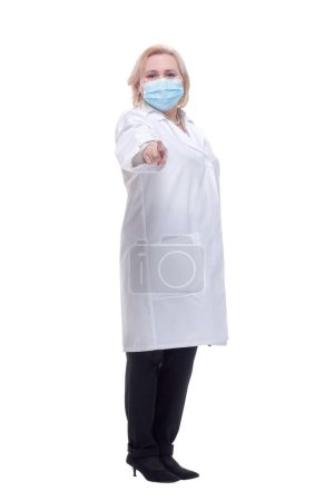 Téléchargez les photos : Femme médecin d'âge moyen portant un masque pointant du doigt vers la caméra et vers vous. Un geste positif et confiant - en image libre de droit