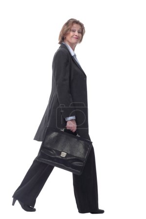 Foto de Sonriente mujer de negocios madura caminando a un lado con maletín aislado sobre fondo blanco - Imagen libre de derechos