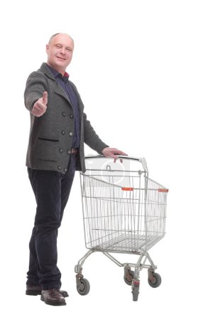 Photo for In full growth.smiling casual man with shopping cart .isolated on a white background. - Royalty Free Image