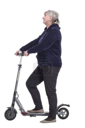 Foto de Vista lateral. una anciana sonriente con un scooter eléctrico mirándote. aislado sobre un fondo blanco. - Imagen libre de derechos